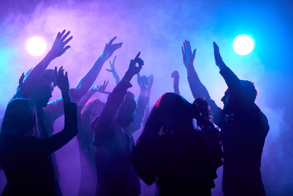 A dancefloor in a nightclub with people dancing on it with their arms in the air