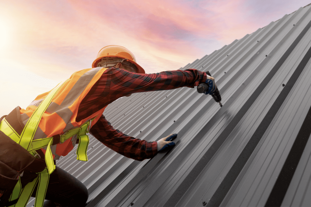 a person on a roof sideways drilling in the roof